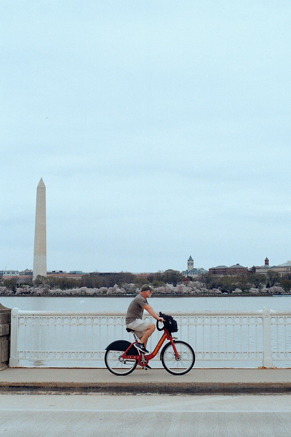 man in white shirt riding bicycle on bridge during daytime