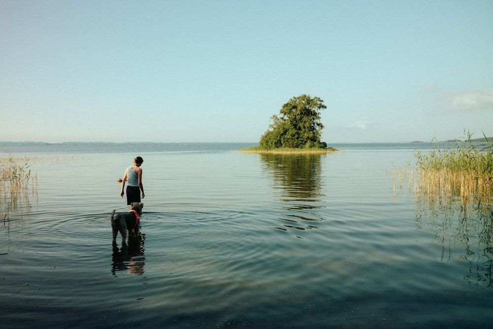 man in white shirt and black shorts standing on body of water during daytime