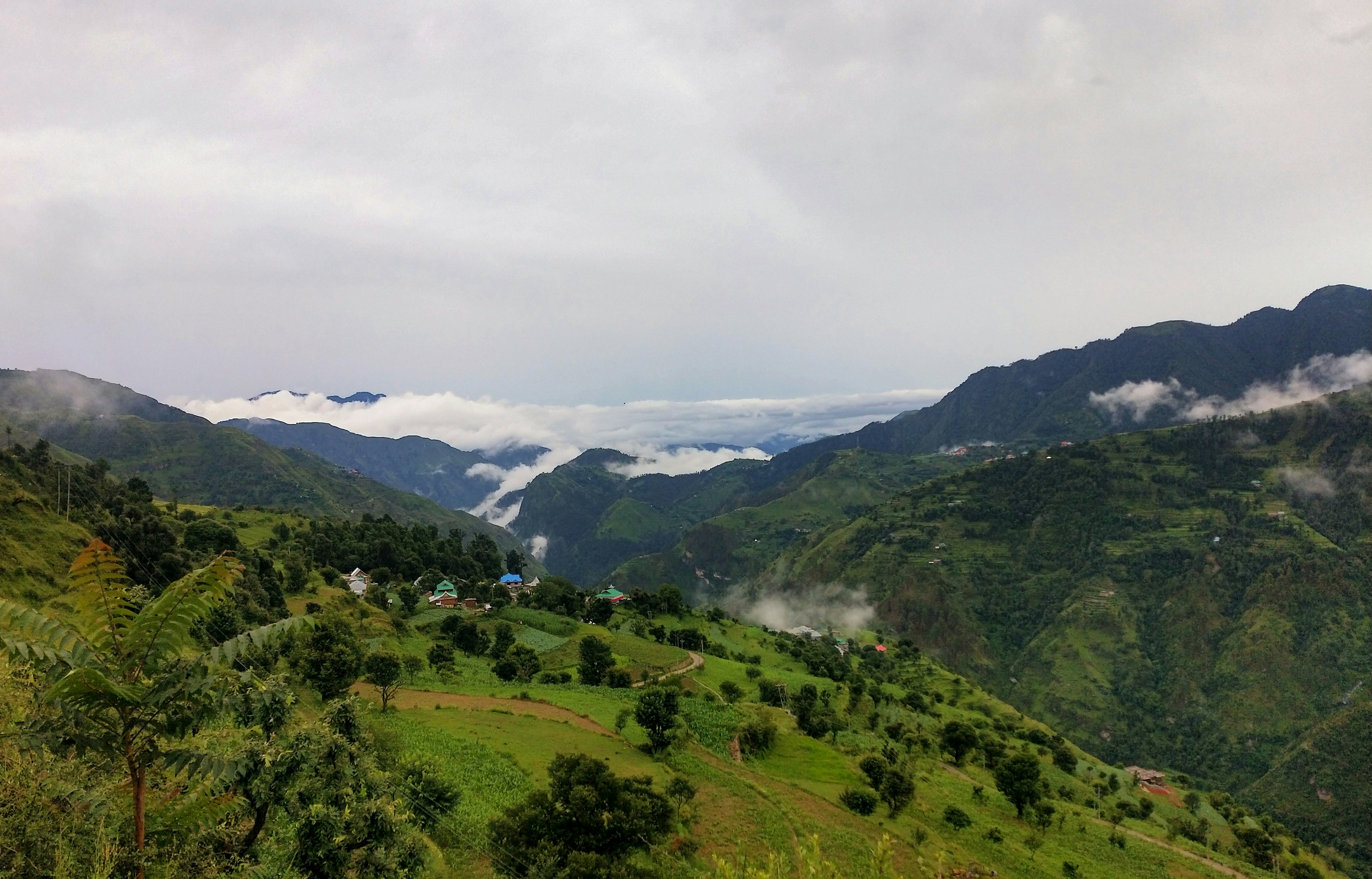 green mountains under white clouds during daytime, A hilly landscape just after rainfall surrounded by clouds.