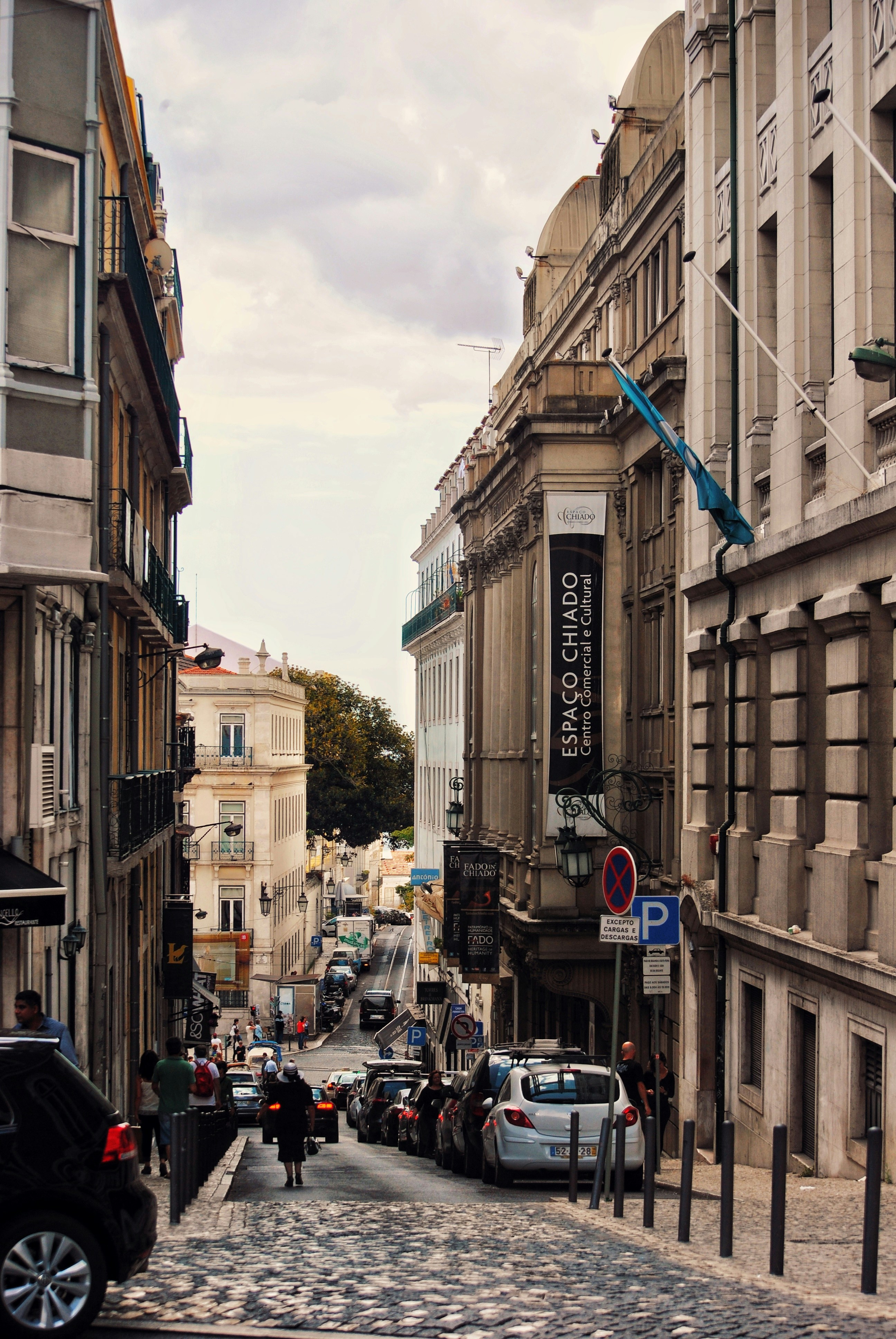 cars parked on side of the road in between buildings during daytime