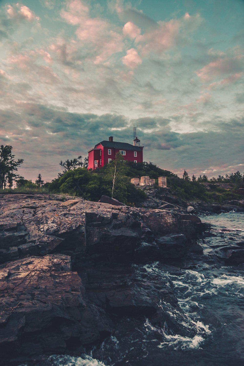 red and white house on rock formation near body of water during daytime