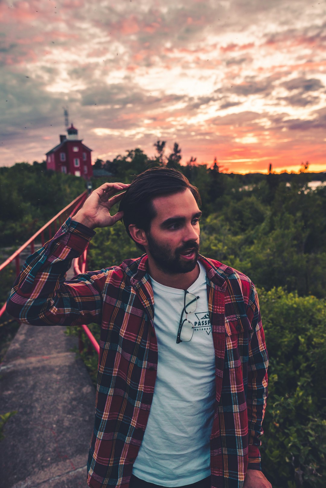 man in red black and white plaid dress shirt standing near green trees during daytime