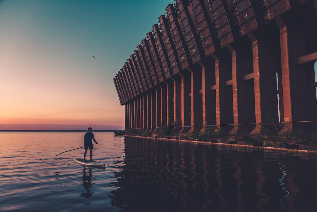 silhouette of person standing on dock during sunset