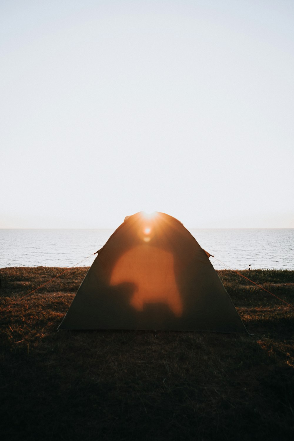 brown tent on brown sand near body of water during daytime