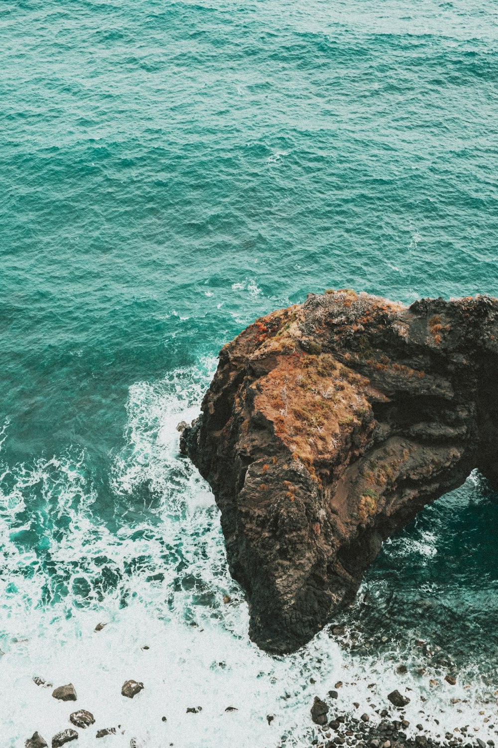 brown rock formation on body of water during daytime