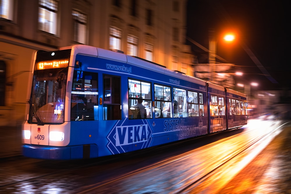 blue and white tram on road during night time
