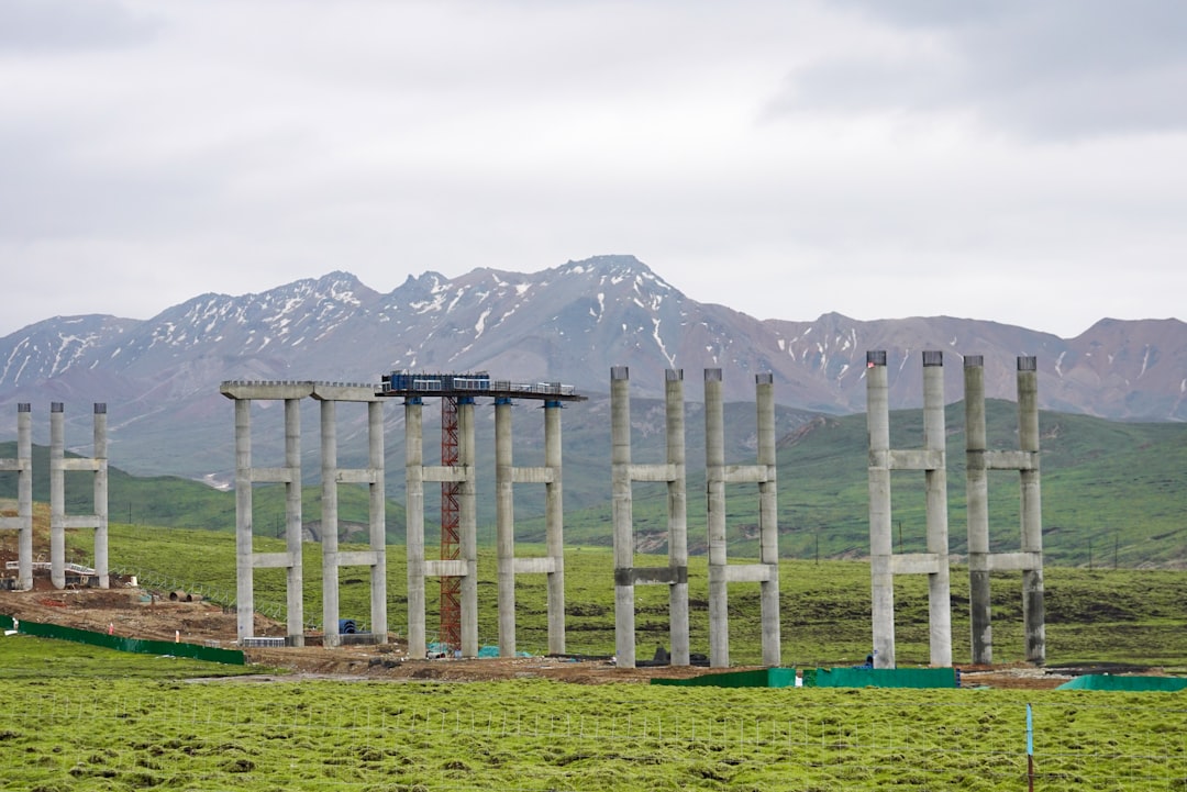 white wooden fence on green grass field near snow covered mountain during daytime