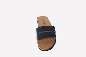 A single brown and black slip-on sandal featuring a textured black strap and a smooth brown footbed with branding or a logo displayed on the upper part of the insole.