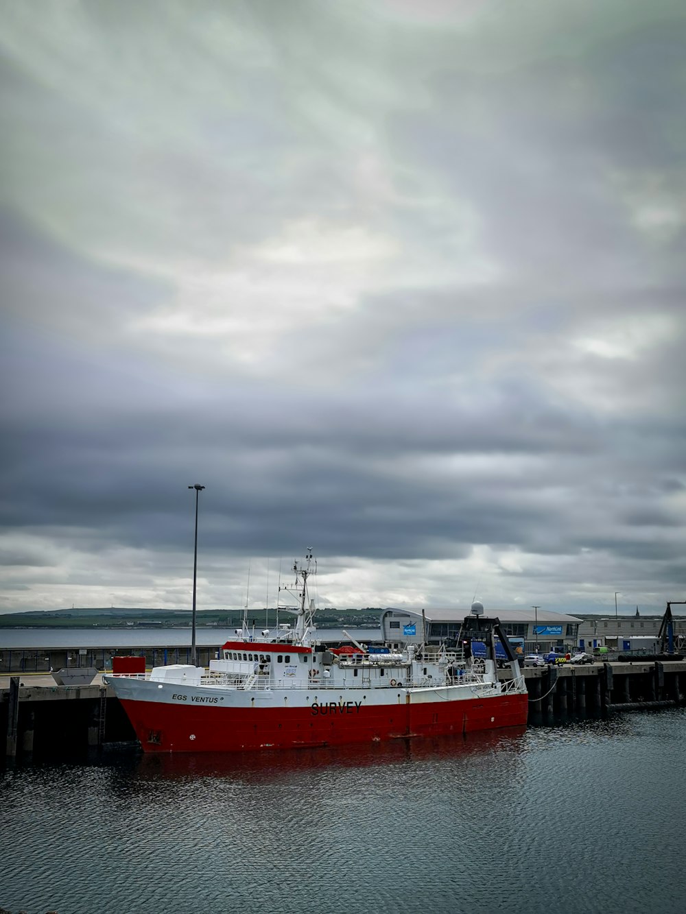 red and white boat on dock under cloudy sky during daytime