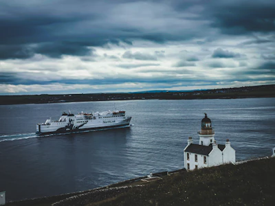 The ferry passing a lighthouse in Orkney’s waters — Orkney, United Kingdom