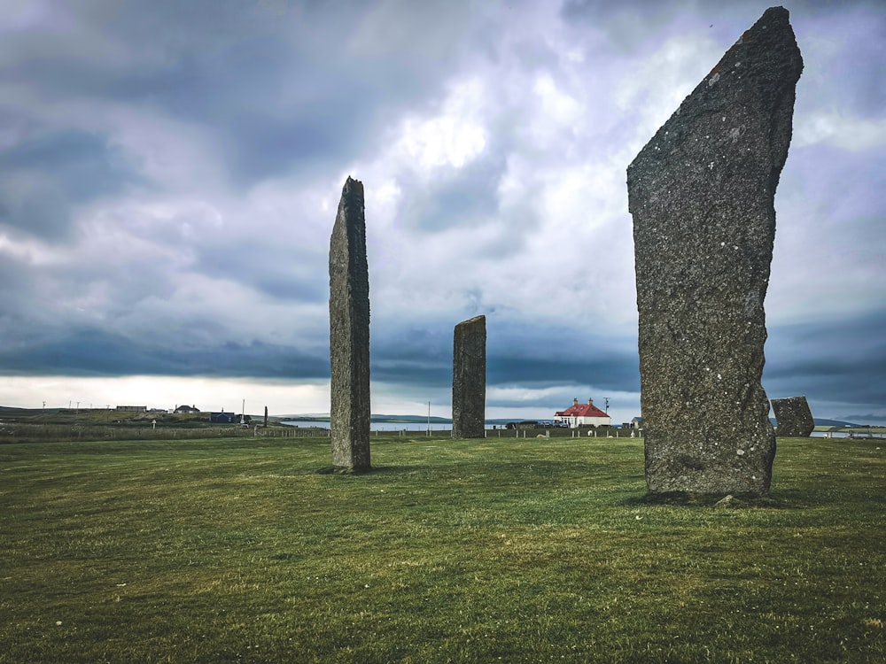 gray concrete pyramid on green grass field under cloudy sky during daytime