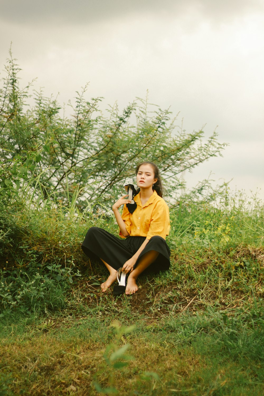 woman in yellow shirt and black skirt sitting on green grass field
