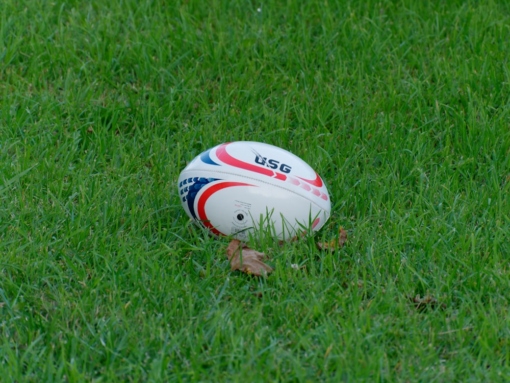Balón de fútbol blanco y azul en el campo de césped verde durante el día