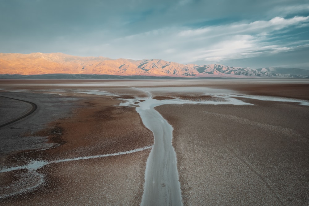 brown and white mountains near body of water under blue sky during daytime