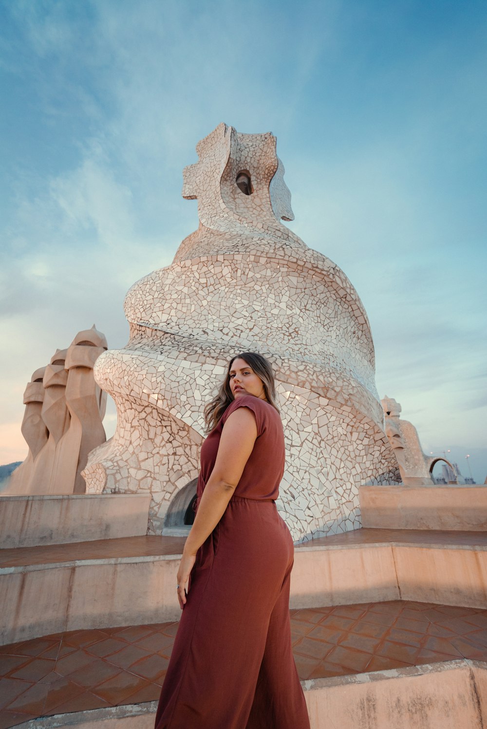 woman in orange sleeveless dress standing near white concrete building during daytime