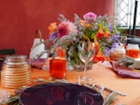 A dining area with a table set for a meal, featuring fresh flowers.
