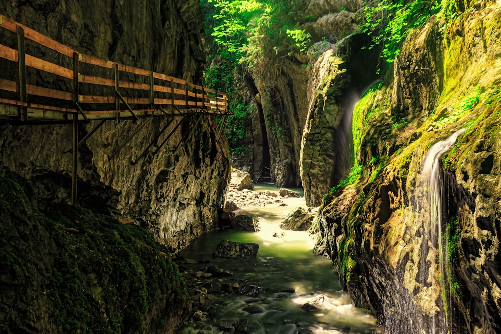 brown wooden bridge over river between rock formation during daytime