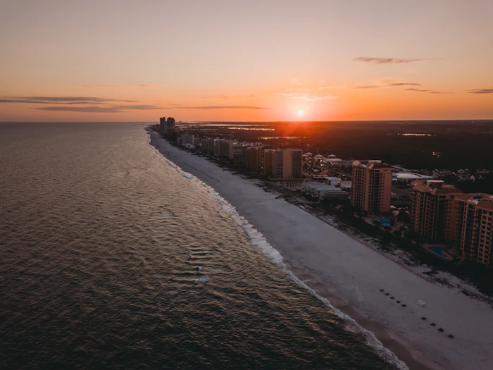 Aerial view of a wide sandy beach lined with hotels at sunset, similar to Isla Verde