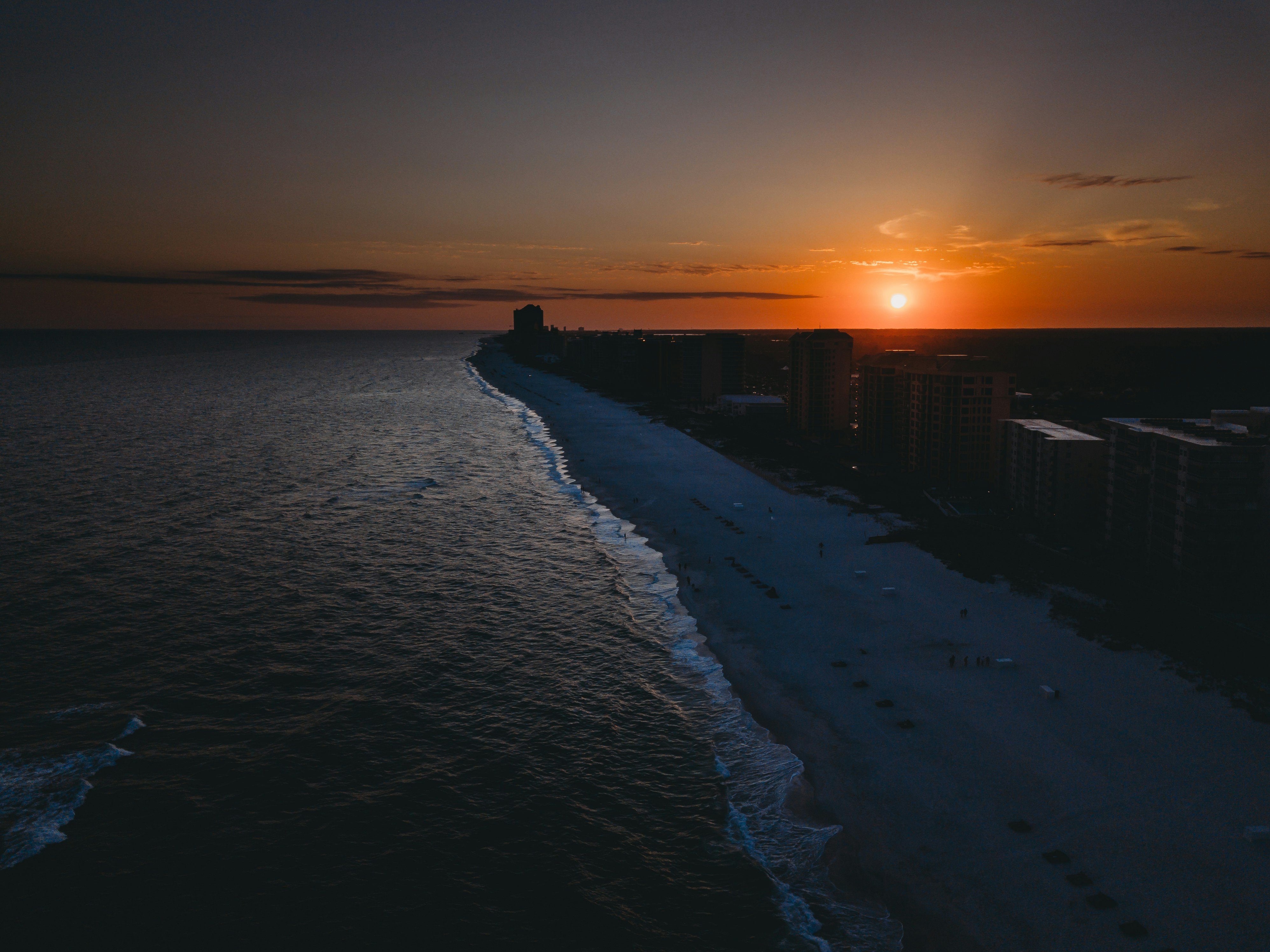 silhouette of people walking on beach during sunset