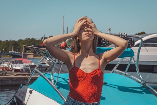 woman in red tank top and blue denim shorts sitting on blue and white boat during