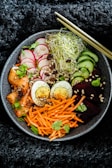 Close-up of a vibrant bowl with colorful Asian fusion ingredients and fresh herbs.