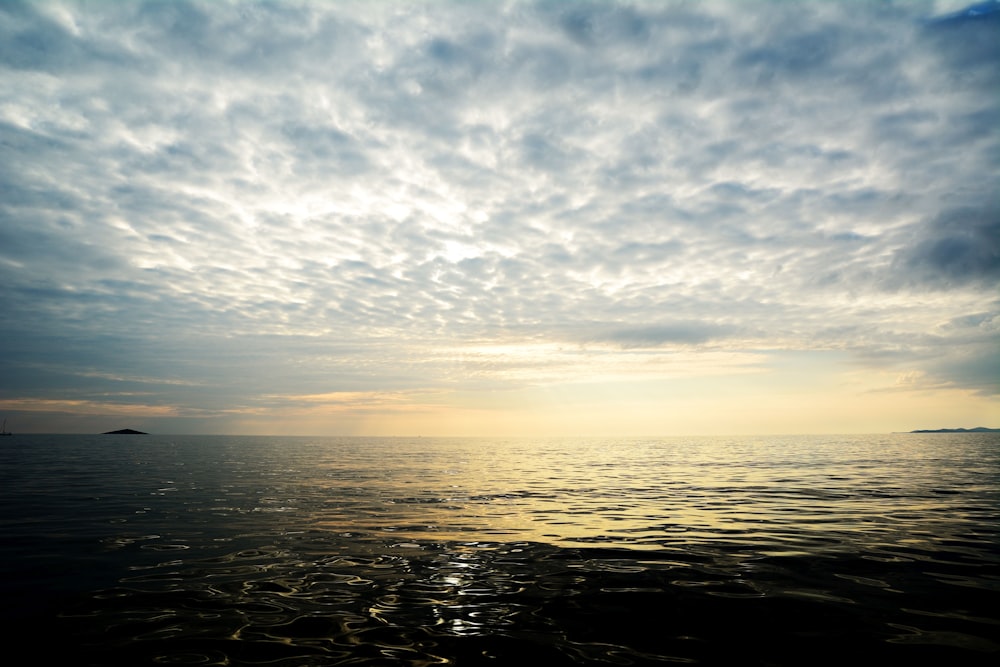 body of water under cloudy sky during sunset