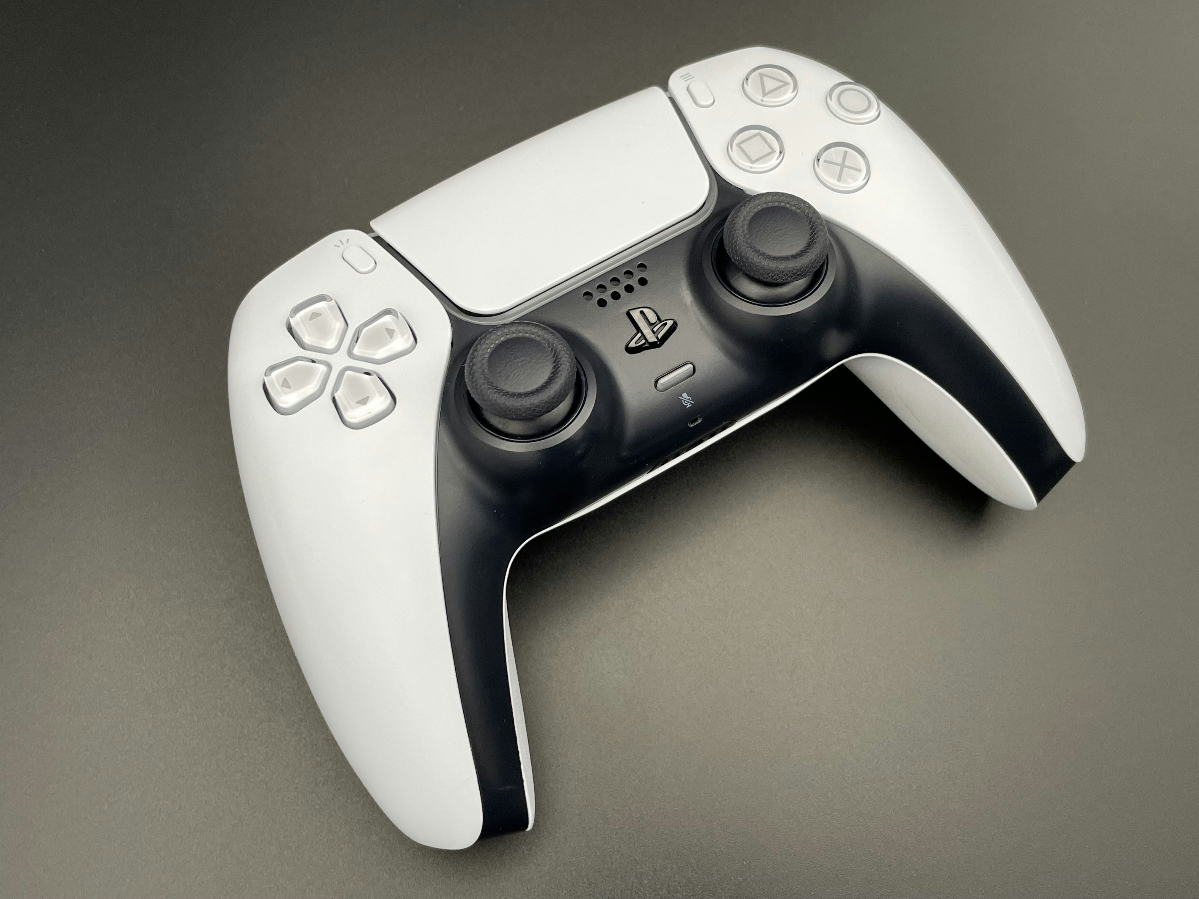 Black PS5 DualSense controller on dark surface with purple ambient lighting