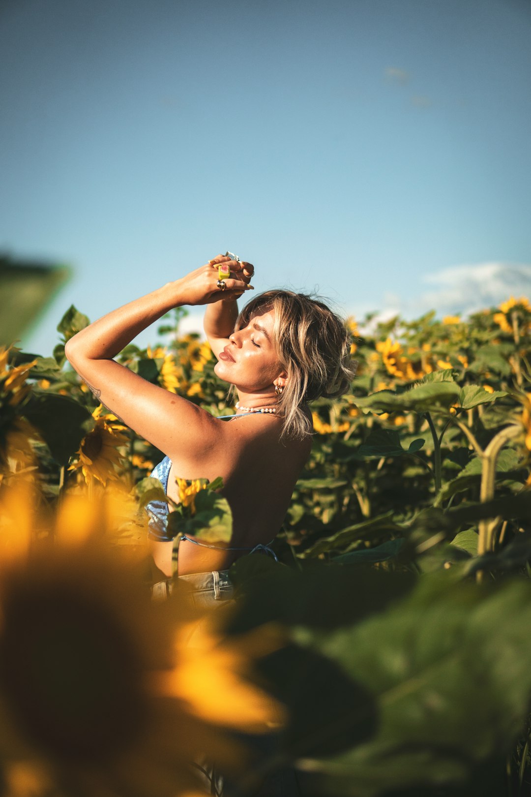 woman in yellow floral tank top standing on green grass field during daytime