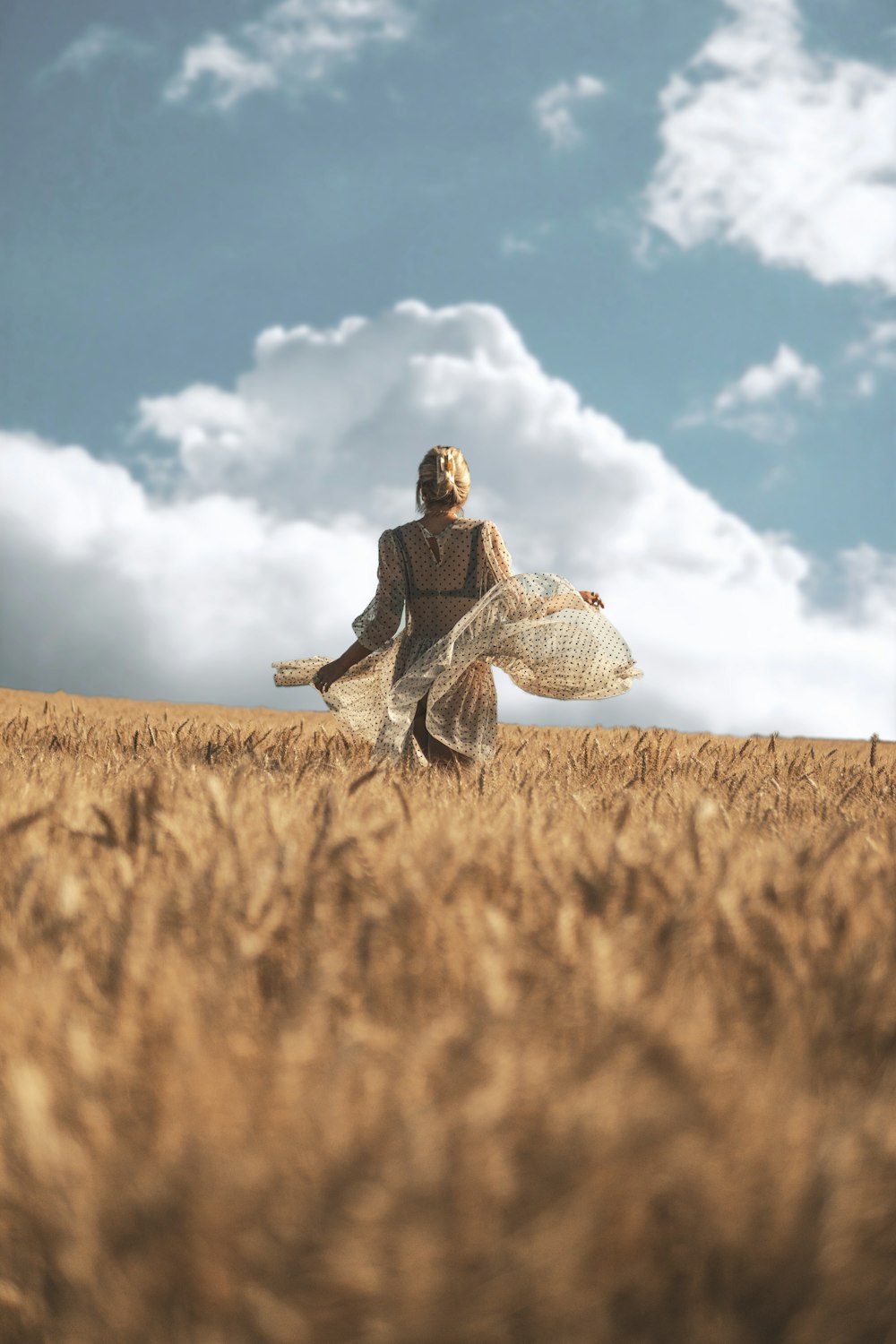 woman in black jacket and gray pants sitting on brown field under blue and white sunny