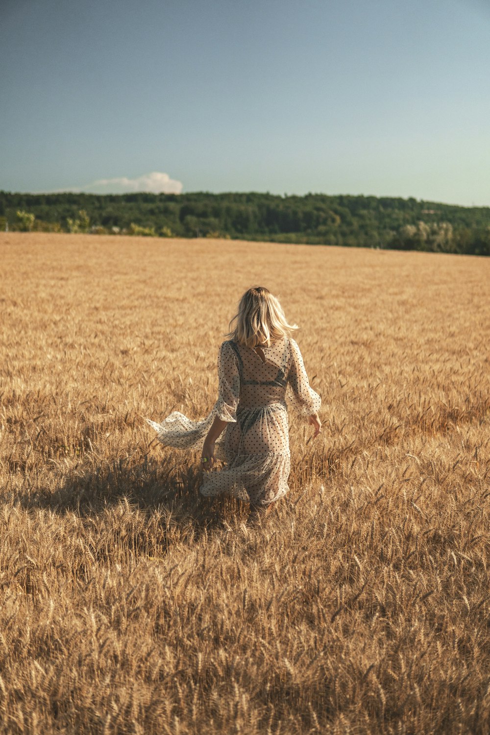 Donna in abito bianco e nero che si siede sul campo di erba marrone durante il giorno