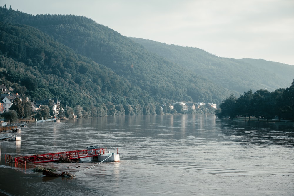 white and red boat on body of water near green mountain during daytime