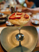 Hands holding a glass of flan topped with fresh berries, inviting to taste.