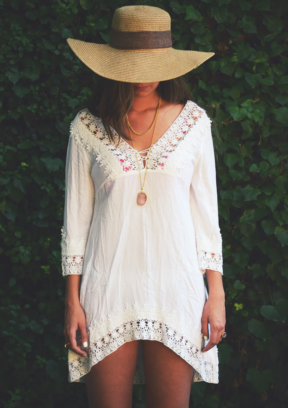 Woman wearing a white crochet-trim peasant dress and straw hat