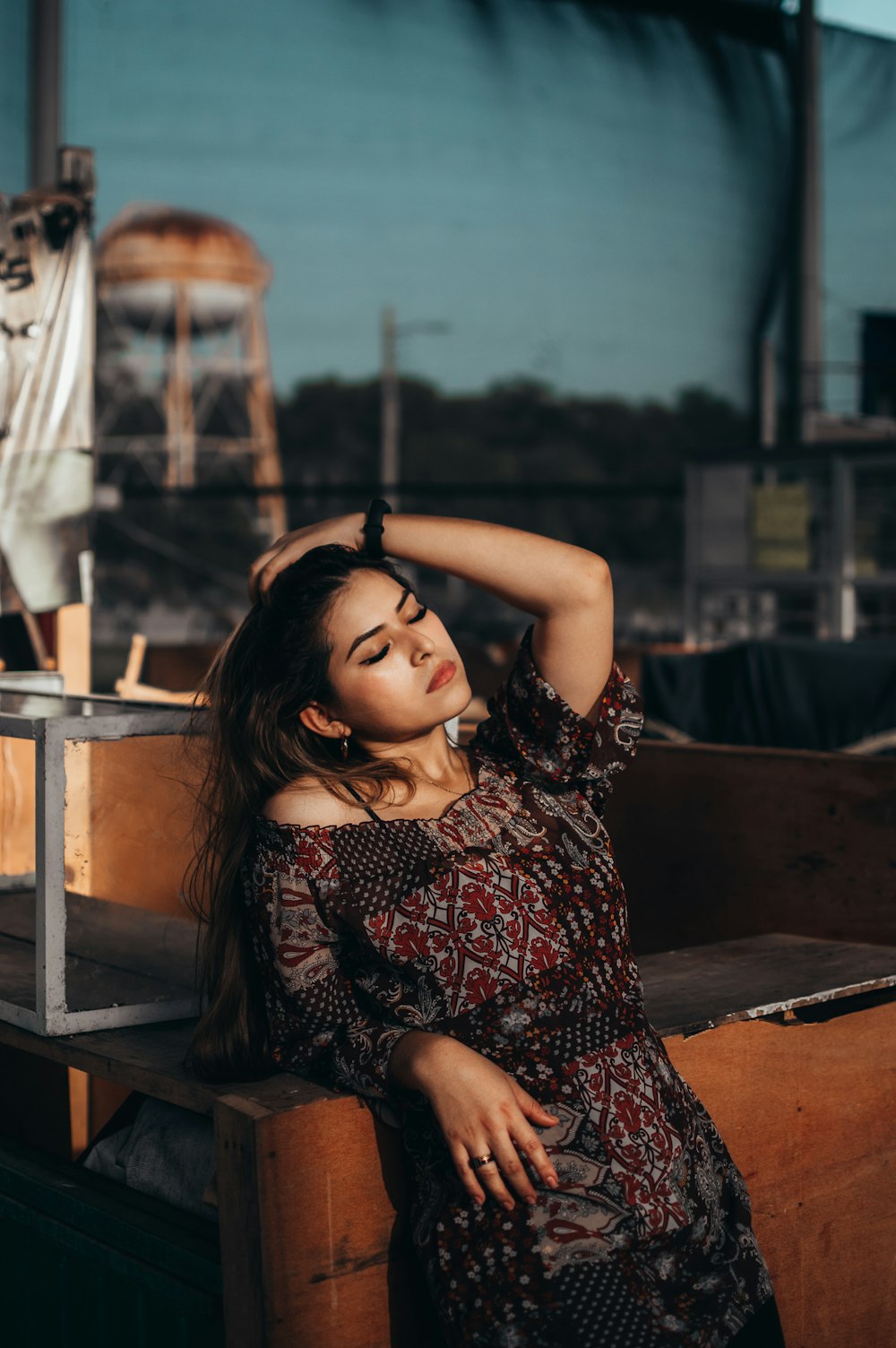 woman in black and red floral sleeveless dress sitting on brown wooden chair