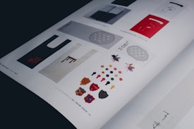 A magazine page featuring various artistic designs including bag templates, colorful geometric shapes, insects, and honeycomb patterns. The artwork is complemented by text in different scripts.