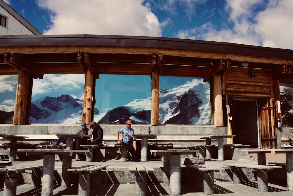 man in blue jacket sitting on brown wooden bench during daytime