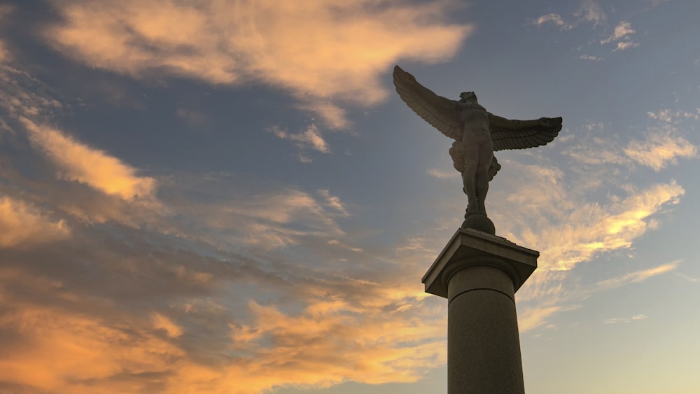 statue of man under cloudy sky during sunset