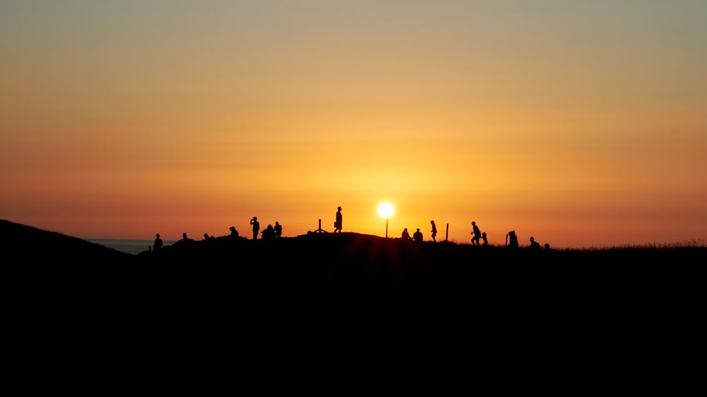 Silueta de personas en el campo durante la puesta de sol