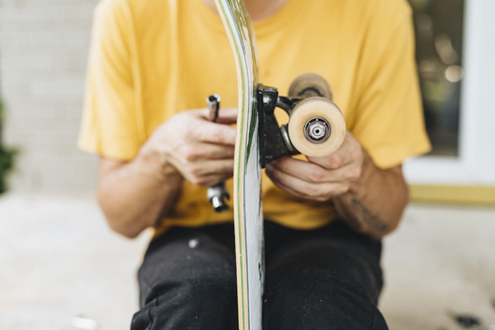 man in yellow shirt holding white and black camera