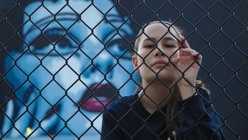 woman in black crew neck shirt leaning on blue metal fence