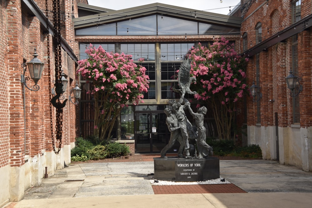 gray concrete statue near red flowers during daytime