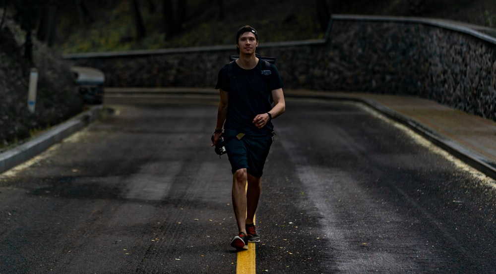 woman in blue crew neck t-shirt and black shorts running on road during daytime