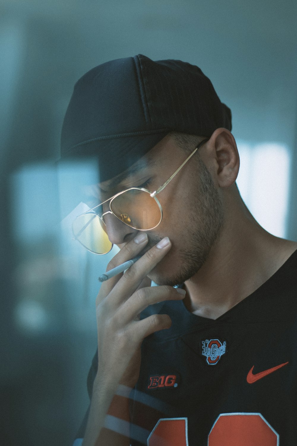 Hombre con camisa negra de cuello redondo con gorra de punto negra y gafas de montura negra