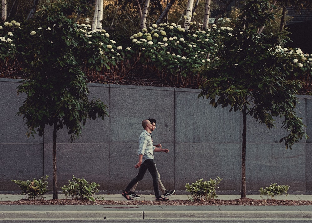 boy in white t-shirt and black pants walking on sidewalk during daytime