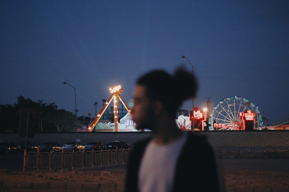 man and woman standing near ferris wheel during night time