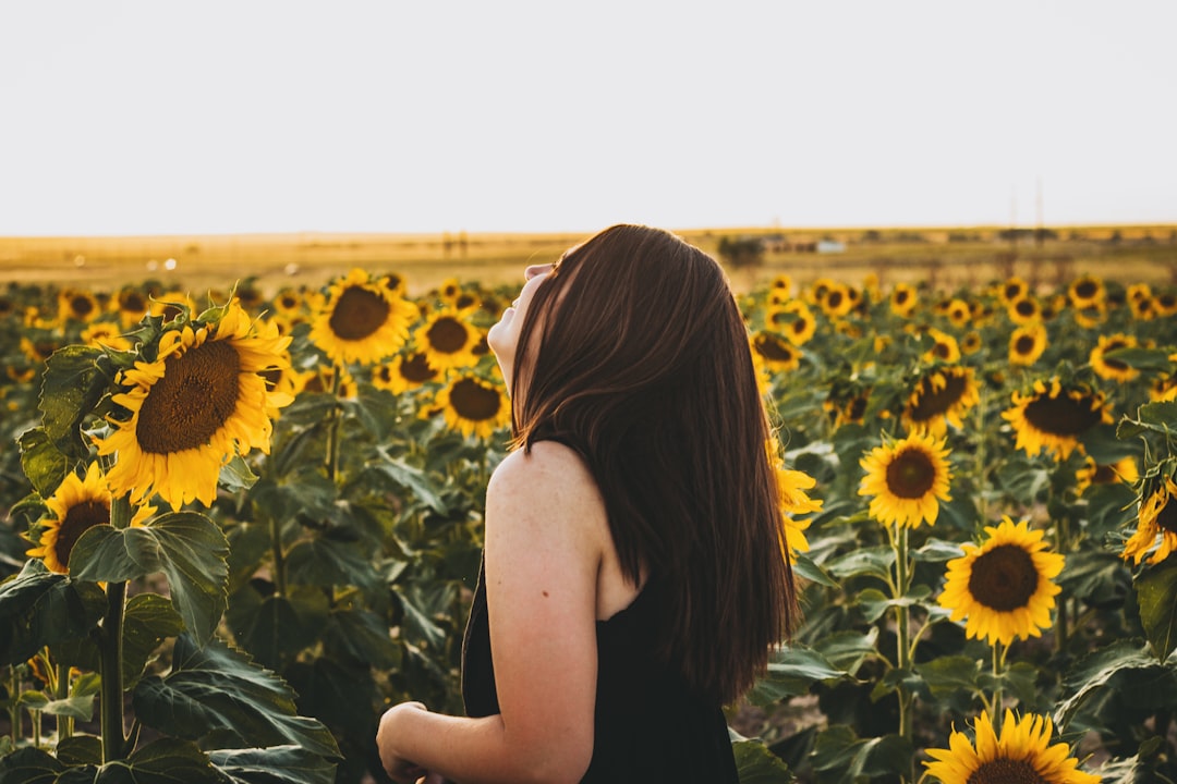 woman in black tank top standing on sunflower field during daytime