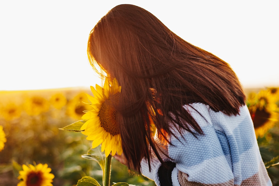 woman in white and black striped shirt holding sunflower