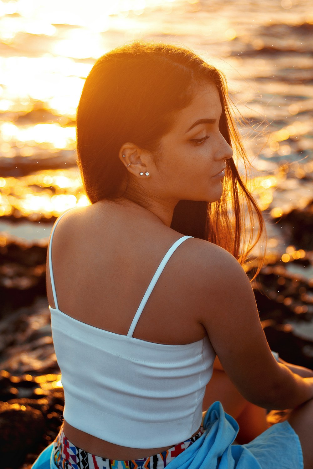 woman in white tank top standing on beach during sunset