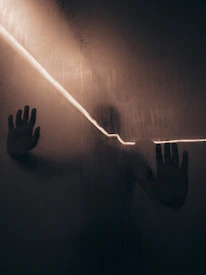 Close-up of a hand pressed against a foggy glass, evoking mystery and secrecy.