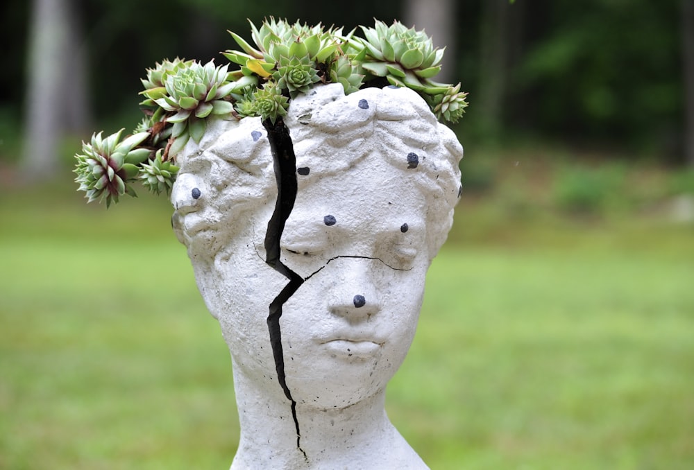 white concrete statue with green plant